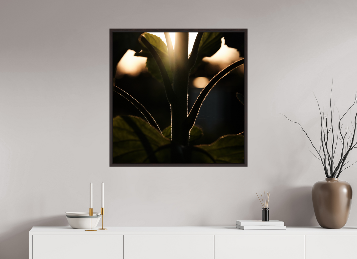 Lifestyle foto van een kunstprint van zonnebloem steel bij zonsondergang ingelijst in een houten galerielijst met schaduwvoeg van 80x80cm.