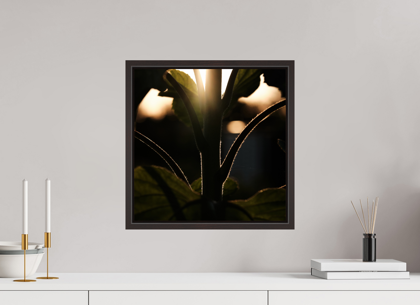 Lifestyle foto van een kunstprint van zonnebloem steel bij zonsondergang ingelijst in een houten galerielijst met schaduwvoeg van 40x40cm.